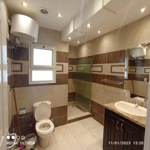 a bathroom with a toilet and a sink and a window at Private 3 bdrm apartment at ElKarma Aqua Beach Reaort in Hurghada