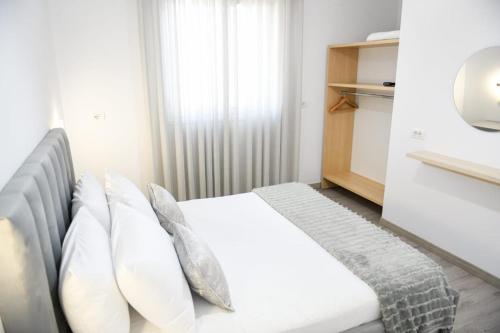 1 dormitorio con 1 cama con sábanas y almohadas blancas en Villa Kaceli en Berat