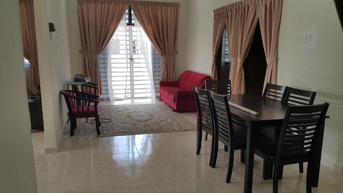 - une salle à manger avec une table, des chaises et un canapé rouge dans l'établissement MJ Homestay Kota Bharu, à Kota Bharu