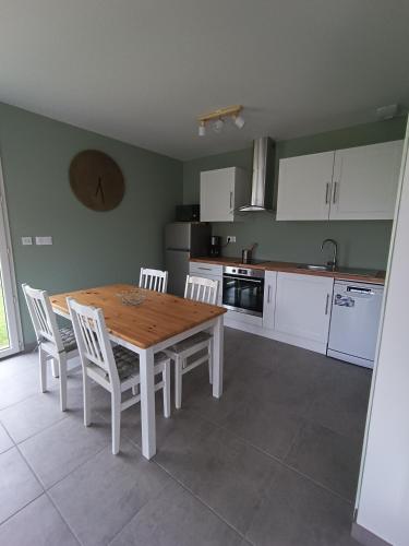 - une cuisine avec une table en bois et des chaises blanches dans l'établissement les galets de Normandie, à Biville-sur-Mer