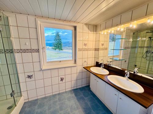 La salle de bains est pourvue de 2 lavabos et d'une fenêtre. dans l'établissement Ferienhaus Am Hofacker, à Aflenz Kurort