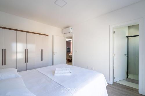 ein weißes Schlafzimmer mit 2 Betten und einem Spiegel in der Unterkunft Apto confortável a 5 min da praia ROT1001 in Itapema