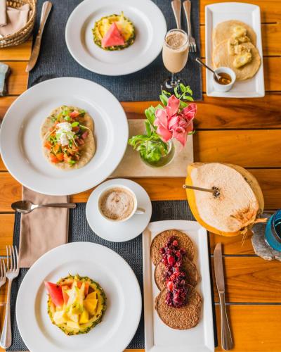 a wooden table with plates of food on it at Kura Boutique Hotel Member of the Cayuga Collection in Uvita