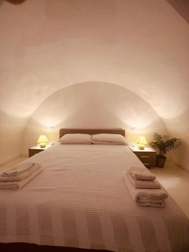 a bedroom with a large white bed with two lamps at Corte Perugia in Matino