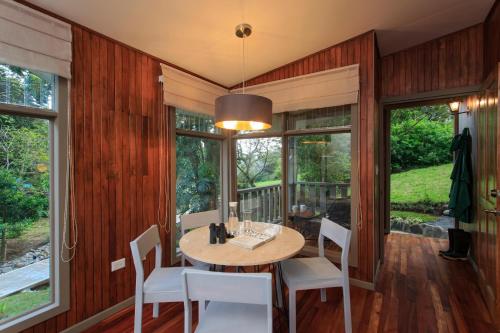 a dining room with a table and chairs and windows at Senda Monteverde Hotel Member of the Cayuga Collection in Monteverde Costa Rica
