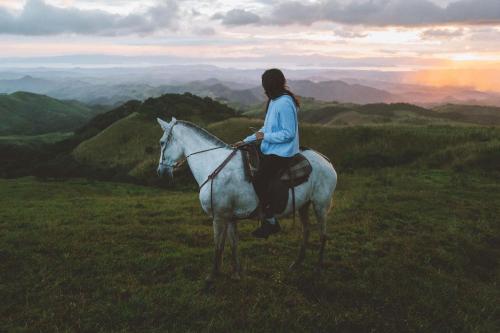 a woman riding a white horse on top of a hill at Senda Monteverde Hotel Member of the Cayuga Collection in Monteverde Costa Rica