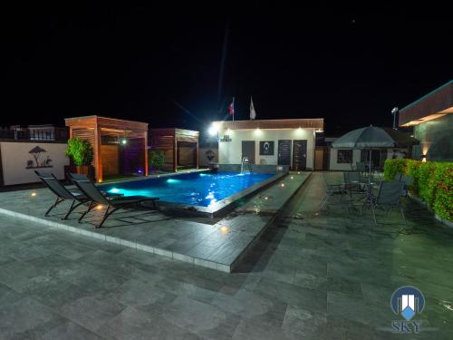 Luxury Sky Residence Double Bedroom في باراماريبو: مسبح في الليل مع كراسي ومبنى