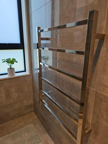 um chuveiro na casa de banho com uma parede de madeira em Tui Nest Garden Unit em Silverdale