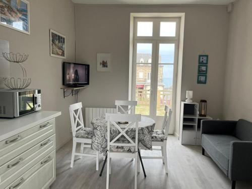 uma sala de estar com uma mesa e cadeiras e um sofá em Appartement d'une chambre a Saint quay portrieux a 100 m de la plage avec vue sur la mer et terrasse amenagee em Saint-Quay-Portrieux