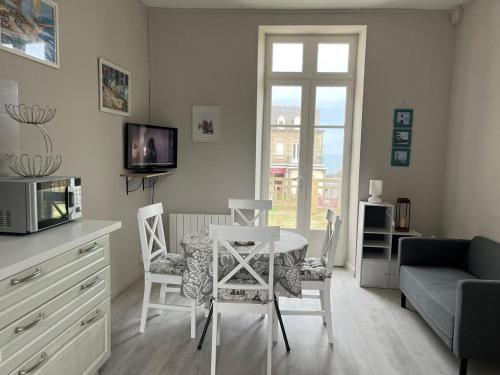 un salon avec une table, des chaises et un canapé dans l'établissement Appartement convivial Saint-Quay-Portrieux 60 m² avec terrasse, à Saint-Quay-Portrieux