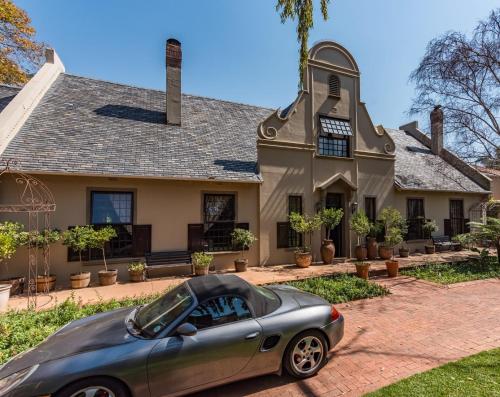 a car parked in front of a house at Houghton Rosebank Cottage with deck overlooking pool in Johannesburg