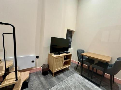 a living room with a television and a table and chairs at Cozy En-suite Loft in Trendy Local in London