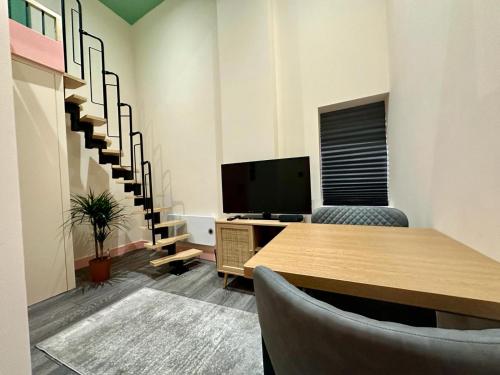 una oficina con escritorio, TV y escaleras en Cozy En-suite Loft in Trendy Local en Londres