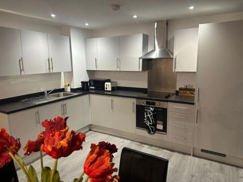 a kitchen with white cabinets and red flowers in a room at Hemel Hives in Hemel Hempstead