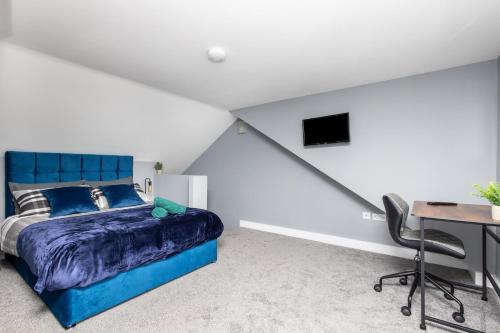 a bedroom with a blue bed and a desk at Lofthouse, Wakefield M1 & M62 - Free Parking & Wi-Fi, Self Check-in, Garden, All Bedrooms Include En-suite, Smart TV & Bluetooth Speaker - Contractors Welcome in Wakefield