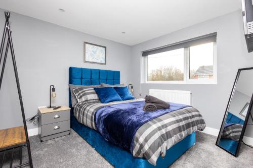 a bedroom with a blue bed and a mirror at M1 M62 Lofthouse, Wakefield - Off Road Parking, Self Check-in, Wi-Fi, En-suite & Smart TV in Every Bedroom - Families, Contractors, Long Stays in Wakefield