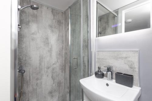 a white bathroom with a sink and a shower at M1 M62 Lofthouse, Wakefield - Off Road Parking, Self Check-in, Wi-Fi, En-suite & Smart TV in Every Bedroom - Families, Contractors, Long Stays in Wakefield