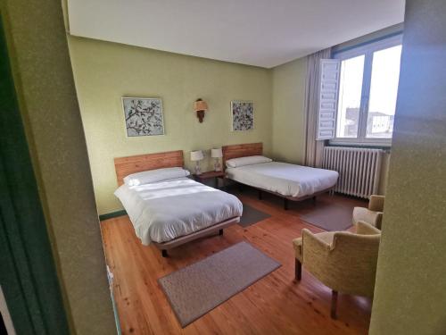 Quintanas de GormazにあるLa Casa Grande de Gormazのベッド2台と椅子が備わる小さな客室です。
