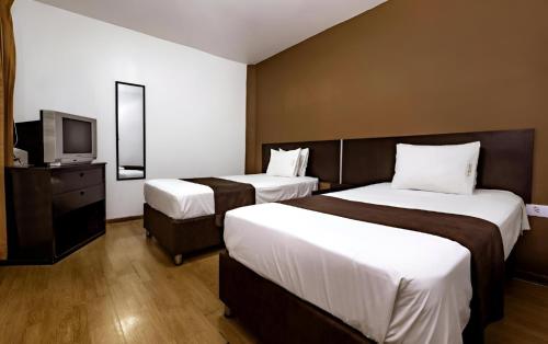トルヒーリョにあるEl Centuriónのベッド2台とテレビが備わるホテルルームです。
