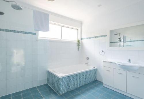 een witte badkamer met een bad en een wastafel bij Stunning Coastal Home Views 1 Hour From Sydney in Wombarra