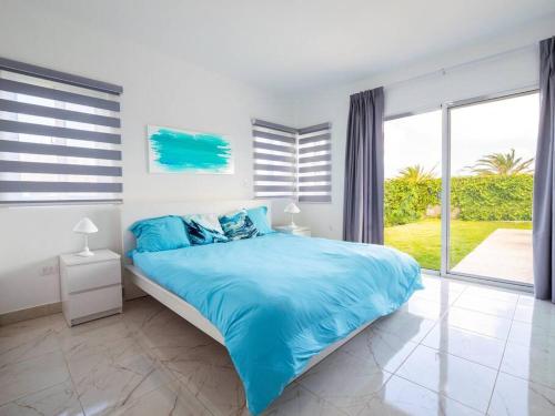 - une chambre avec un lit bleu et une grande fenêtre dans l'établissement Villa Justin, à Laguna del Higüero