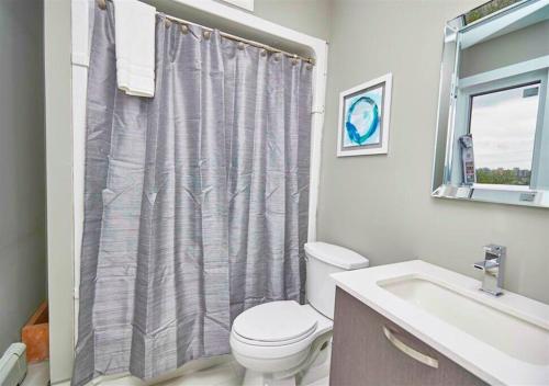 e bagno con servizi igienici, lavandino e tenda per la doccia. di Luxury Boutique 2 Bedroom Condo - 1B a Niagara Falls