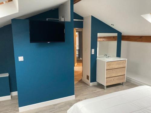 a bedroom with a blue wall with a sink and a tv at Gîte Bassin d'Arcachon, piscine couverte chauffée in Gujan-Mestras