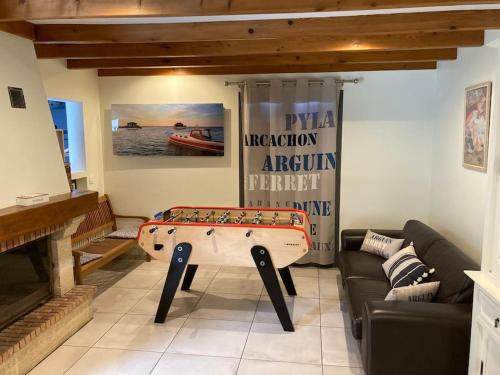 a living room with a table with a board on it at Gîte Bassin d'Arcachon, piscine couverte chauffée in Gujan-Mestras