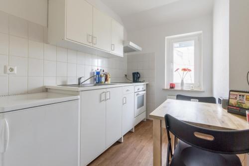 uma cozinha com armários brancos e uma mesa de madeira em Private Rooms em Hanôver