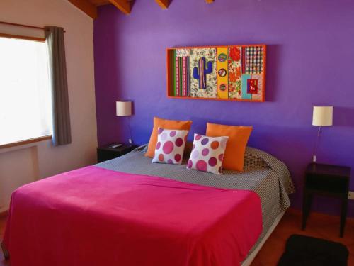 ein lila Schlafzimmer mit einem rosa Bett mit Kissen in der Unterkunft La Casa del Abuelo Hotel Boutique in Purmamarca