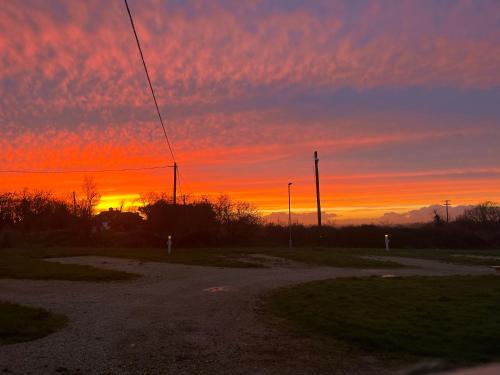a sunset in a field with the sun setting at Coral Gables Guesthouse & Campsite in Rosslare
