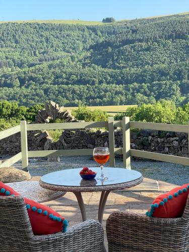 une table et deux chaises avec un verre de vin dans l'établissement The Cowshed, à Llangollen