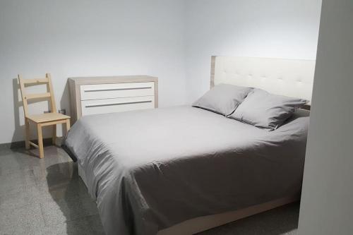 een slaapkamer met een bed en een houten stoel bij Apartamento con amplia terraza en Candelaria in Candelaria