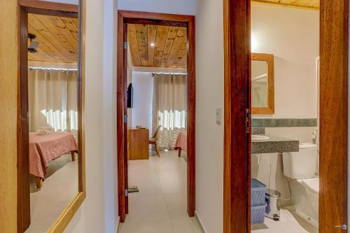 Ein Flur führt zu einem Badezimmer mit Waschbecken und Spiegel. in der Unterkunft Apartamentos Orla Itacaré - Casa Flor in Itacaré