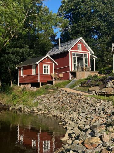 une maison rouge assise à côté d'une rivière dans l'établissement Forest house, à Ljungskile