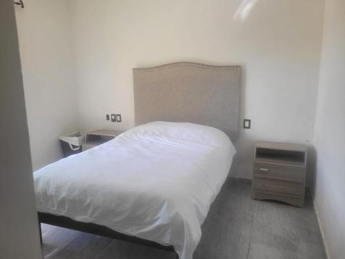 a bedroom with a white bed and a night stand at Cabaña Na-tatik in Ocosingo