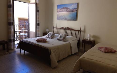 a bedroom with two beds and a balcony at Sicilian Dream Apartments in Cefalù