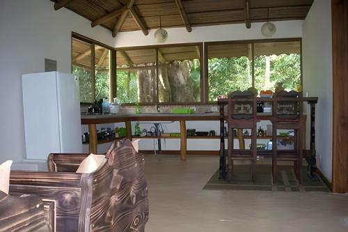 a living room with a couch and a kitchen with windows at Jungle Dreamz in Manzanillo