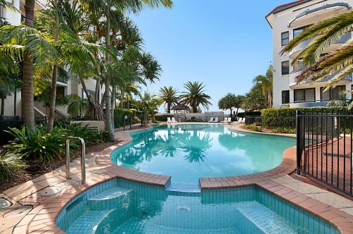 a large swimming pool with palm trees and a building at Sandcastles On The Broadwater in Gold Coast