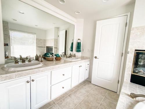 a white bathroom with two sinks and a mirror at Resort style back yard heated pool and spa in Encinitas