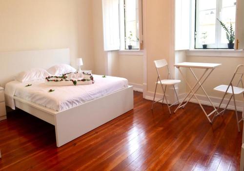 ein Schlafzimmer mit einem weißen Bett sowie Holzböden und -fenster in der Unterkunft Matching Loures Guest House in Loures