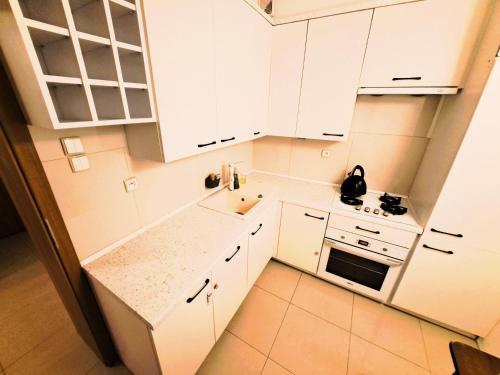 a small kitchen with white cabinets and a sink at Apartament z ogrodem w sercu Torunia in Toruń
