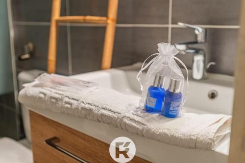 - un lavabo dans la salle de bains avec 2 bouteilles sur une serviette dans l'établissement R'Apparts T2 Le Jardin Charmant, à Grenoble