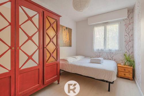 une chambre avec un lit et une grande armoire rouge dans l'établissement R'Apparts T2 Le Jardin Charmant, à Grenoble