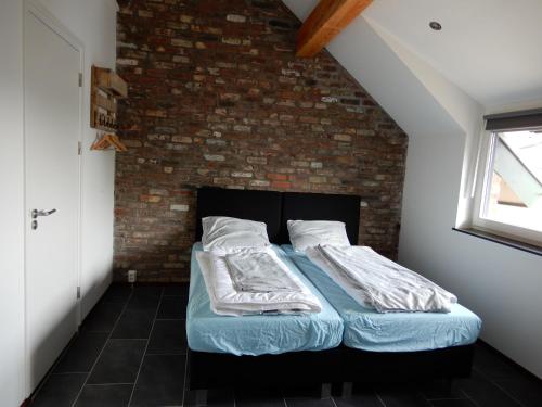 a bed in a room with a brick wall at De Schuur in Walem