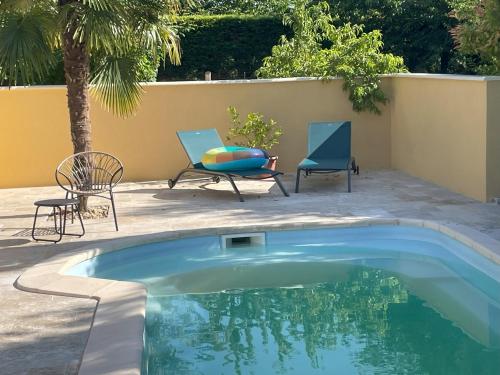 une piscine avec deux chaises et une table dans l'établissement Jardin d'Essais (Gîte), à Saint-Michel-de-Montaigne