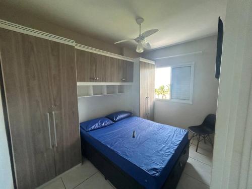 - une chambre avec un lit bleu et une fenêtre dans l'établissement Pé na areia, Solemar Praia grande, à Praia Grande