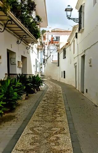 an empty alley with white buildings and plants at Posada Puente Romano in Sedella