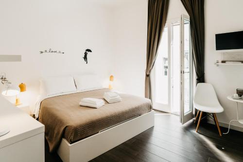 a white bedroom with a bed and a white chair at Le Contrade Vico Alba in Monopoli