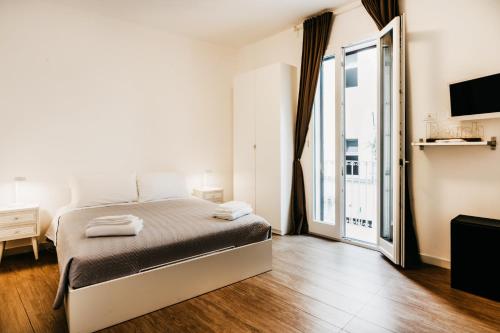 Dormitorio blanco con cama y ventana grande en Le Contrade Vico Alba, en Monopoli